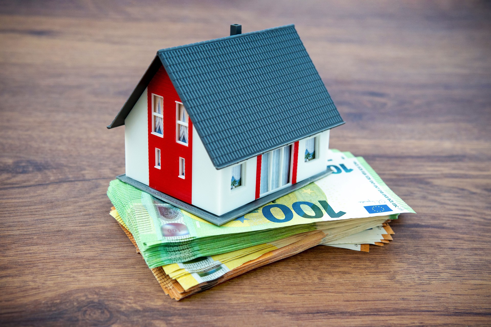 Real estate investment: Model house on Euro bills – Financial planning and wealth building